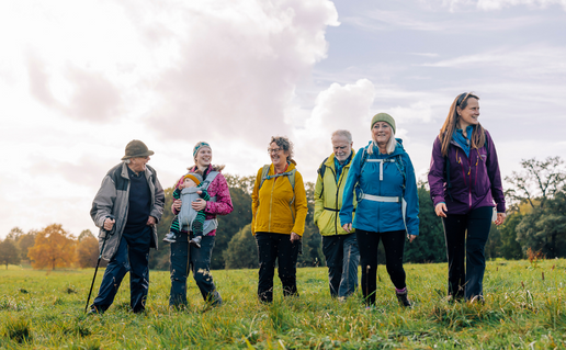 A group of six men and women walking in a field on a cloudy day